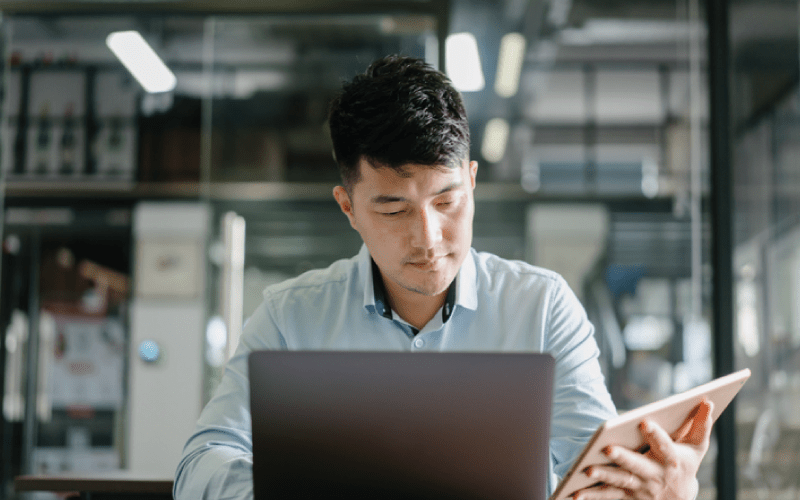 male-employee-reviewing-work-information-on-laptop-and-tablet-800x500px